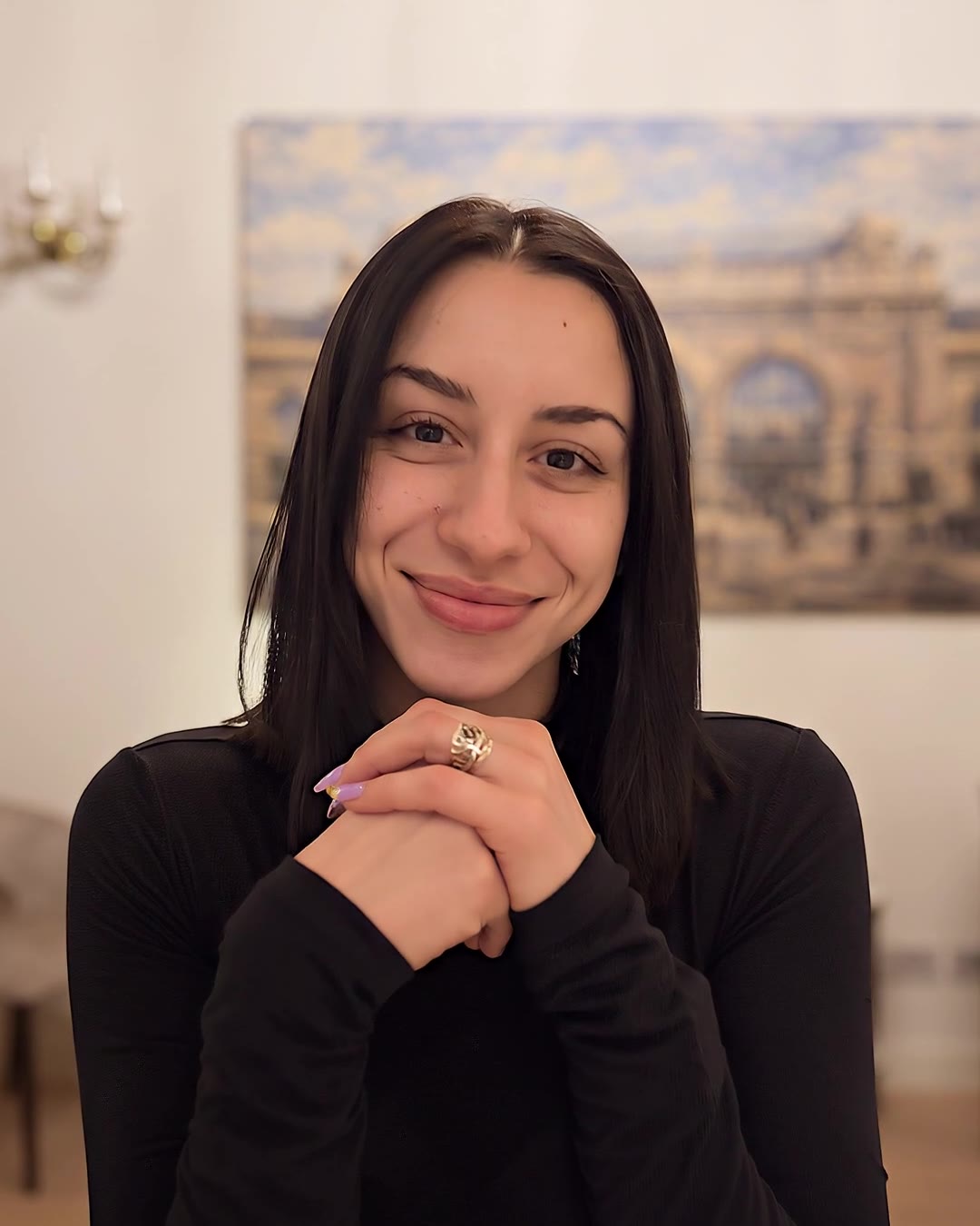 Andreea Mărețu, zâmbind, cu mâinile împreunate, la o masă