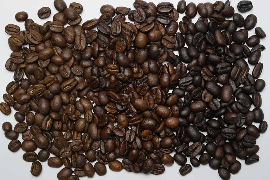 Boabe de cafea în trei grade de prăjire: blonde în stânga, medium la mijloc, dark în dreapta